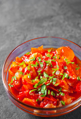 Letcho with tomatoes, peppers and carrots in glass bowl on Dark grey black slate background