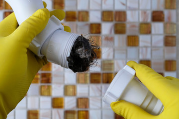 Elimination of blockage in sewer pipes. Hands in yellow gloves disassemble and clean the sink...
