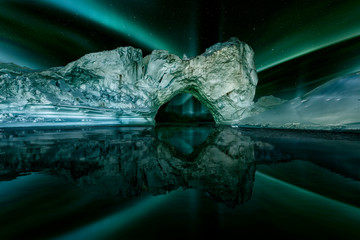 iceberg floating in greenland fjord at night with green northern lights © the_lightwriter