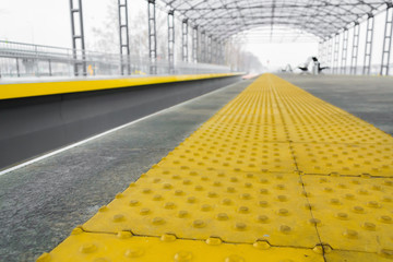 Yellow stop line for blind  people at railroad station in perspective