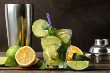 Mojito cocktail in a glass glass with lime, mint and lemon and bar accessories on a wooden brown table. cooking mojito.