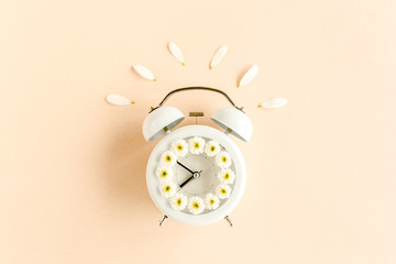 Fototapeta na wymiar Composition-summer time from clock and chamomile flowers on beige background. Flat lay, top view 