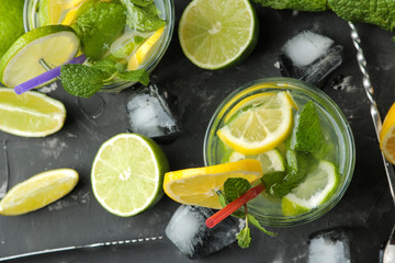 Mojito cocktail in a glass glass with lime, mint and lemon and bar accessories on a dark concrete background. make a mojito.