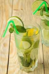 Mojito cocktail in a glass glass with lime, mint and lemon and on a natural wooden table. make a mojito.