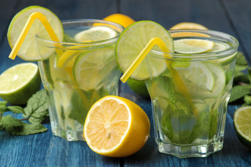 Mojito cocktail in a glass glass with lime, mint and lemon on a blue wooden table. make a mojito.