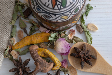 Close-up of spice for tea with glass with infusion, decorated pot of colors and wooden spoon