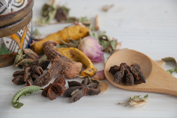 Close-up of spices for tea with wooden spoon and white wooden background