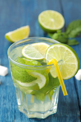 Mojito cocktail in a glass glass with lime, mint and lemon on a blue wooden table. make a mojito.