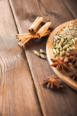 Seasoning on a textured wooden background close-up and copy space. Cinnamon, star anise, fennel, cloves, seasoning tea masala as a texture