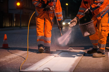 Traffic line painting. Workers are painting white street lines on pedestrian crossing. Road cones...