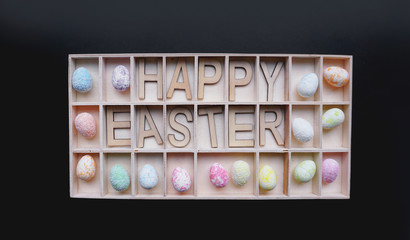 Easter eggs. Happy easter text. Holidays decoration black background. Decor elements in wooden containers