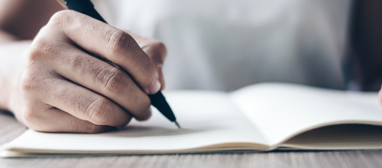 Businesswoman writing on notebook in office, hand of woman holding pen with signature on paper...