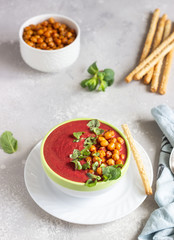 Spring detox beetroot soup with mint, coconut milk and baked chickpeas on a light grey concrete background, copy space. Dieting, clean eating, weight loss, vegetarian food concept.