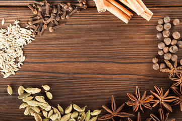 Seasoning on a textured wooden background close-up and copy space. Cinnamon, star anise, fennel, peppercorns, cloves, tea masala seasoning as a texture