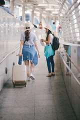 Two happy asian girls dragging luggage suitcase bag. Travel concept.