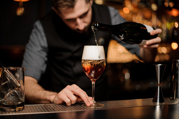 Bartender mixing a delicious cocktail pouring alcohol from the bottle
