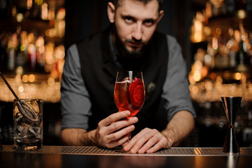 Bartender serving a delicious cocktail with a decor of red slice