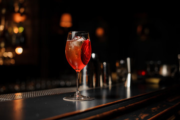 Delicious cocktail decorated with a red vegetable slice on the bar stand