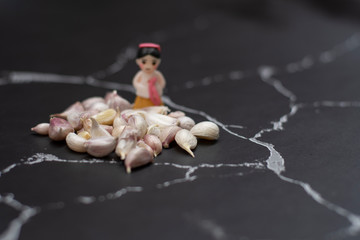 thai garlic (Allium sativum) bulb pile and miniature chief on black background, dark tone, selective focus,