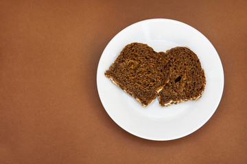 Sliced rye bread on the white plare and brown background. Whole grain rye bread with seeds