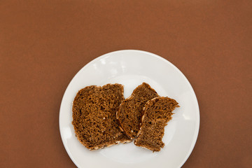 Sliced rye bread on the white plare and brown background. Whole grain rye bread with seeds