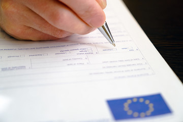 Schengen visa, questionnaire. Hand with pen completing a questionary.