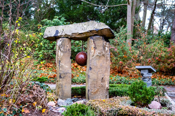 modernes Grabmal im asiatischen Stil in Form eines Dolmen mit hängender Granit Kugel in der Mitte auf dem Friedhof in Berlin Frohnau
