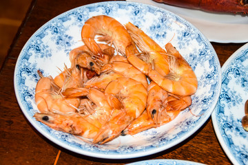 huge boiled red king prawns lie on blue plate dish
