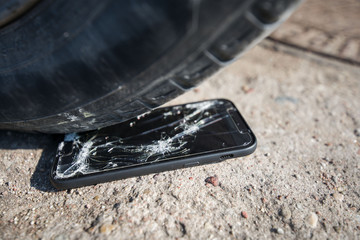 Broken and damaged smartphone with cracks on glass screen laying on ground. Accident. Cell phone...