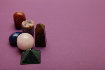 Magic stones and crystals of different shapes and colors lying in bulk on a bardic background.