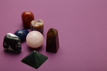 Magic stones and crystals of different shapes and colors lying in bulk on a bardic background.