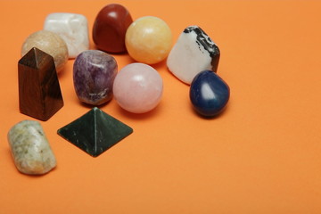 Magical stones and crystals of various shapes and colors lying loose on a yellow background