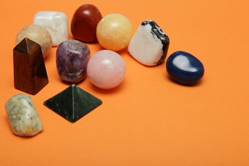 Magical stones and crystals of various shapes and colors lying loose on a yellow background