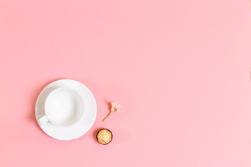 Cup, candy and flower on living coral background with copy space. flat lay.