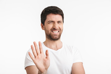 Image of emotional man 30s with bristle in casual t-shirt rejecting and doing stop gesture