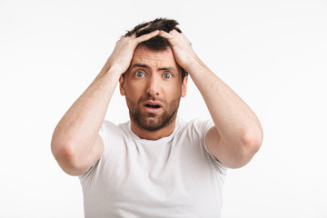 Image of shocked man 30s with bristle in casual t-shirt frowning and grabbing head