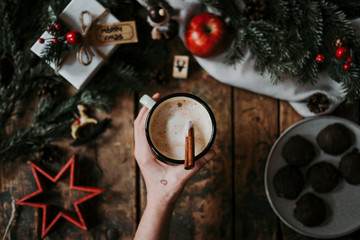 Top view of woman holding coffee cup over Christmas decoration