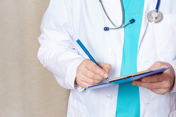 A man in a white medical robe takes notes. Close-up, cropped doctor with stethoscope and tablet for records.