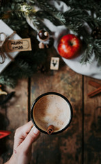 Top view of woman holding coffee cup over Christmas decoration