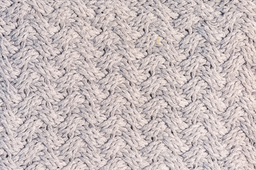 Knitted texture with an unusual pattern close-up. Wool fabric. Gray blank background for layouts.