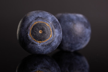 Group of two whole fresh sweet purple blueberry american isolated on black glass