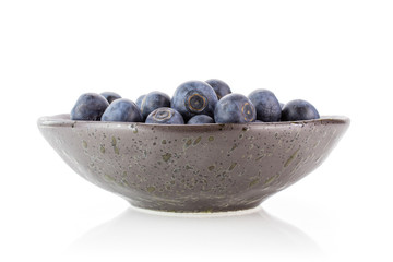 Lot of whole fresh sweet purple blueberry american in a grey ceramic bowl isolated on white background