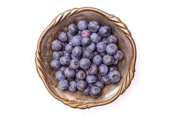 Lot of whole fresh sweet purple blueberry american in old iron bowl flatlay isolated on white background