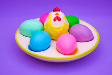Colorful Easter eggs in a ceramic egg stand on a purple background.