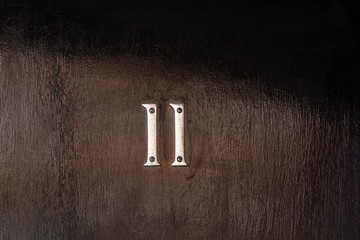 Very dark house door with a simple and elegant number 11 with the eleven in silver metal
