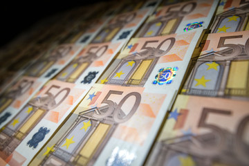 50 euro paper money on black background. Hundreds of banknotes. Concept of cash flow, finances, rich people, millionaire and successful business. 