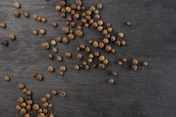 Lot of whole dry brown allspice berries flatlay on grey stone