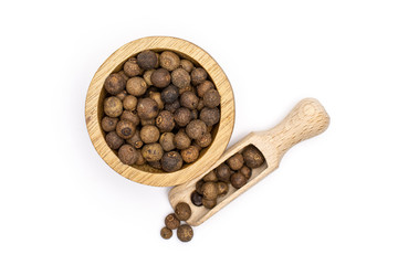 Lot of whole dry brown allspice berries with wooden bowl and wooden scoop flatlay isolated on white background