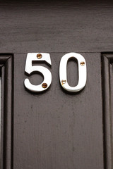 50 on a black house door with he fifty in silver metal numbers