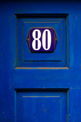 Royal blue enamel sign with the number 80 on it in white where the eighty is a house number
